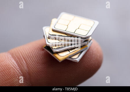 Stacked Of Nano Sim Cards On Person's Finger Stock Photo