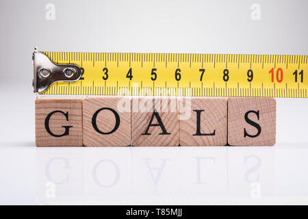 Yellow Measuring Tape Over The Wooden Goals Blocks Stock Photo