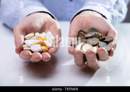 Man Holding Pills, Capsules In One Hand And Coins In Other Hand Stock Photo