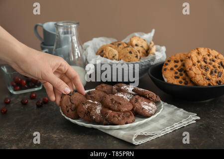Woman taking tasty cookie from plate Stock Photo