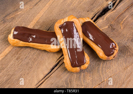 Eclairs with chocolate topping  on wood background. Stock Photo
