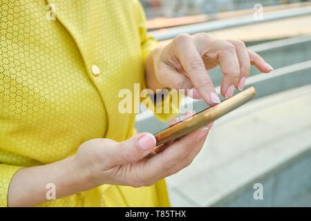 Closeup of womans hand with smartphone, fingers on touchscreen, text message. Stock Photo