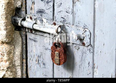 Rusty padlock, securing iron bolt on an older Devon Farm Cottage Stock Photo