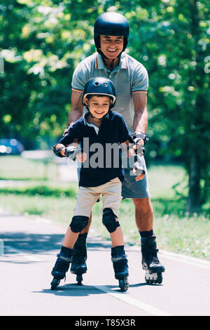 Grandfather teaching grandson to roller skate Stock Photo