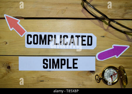 Complicated or Simple opposite direction signs with eyeglasse and compass on wooden vintage background. Business and education on inspiration concepts Stock Photo