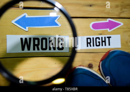 Right or Wrong opposite direction signs in magnifying with sneakers and eyeglasses on wooden vintage background. Business and education concepts Stock Photo
