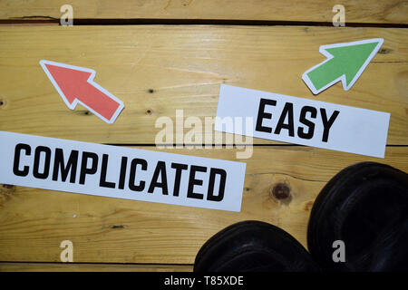 Complicated or Easy opposite direction signs with boots on wooden vintage background. Business and education concepts Stock Photo