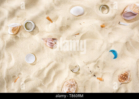 top view of seashells, bottle caps, scattered cigarette butts, plastic bottle caps on sand Stock Photo