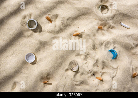 top view of seashells, bottle caps, scattered cigarette butts, plastic bottle caps on sand Stock Photo