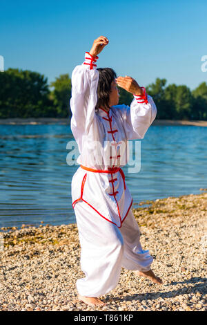 Women practicing tai chi by lake Stock Photo