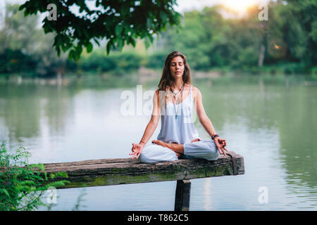 Woman meditating by a lake Stock Photo