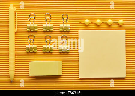top view of pen, paper clips and colorful arranged office stationery supplies on yellow Stock Photo