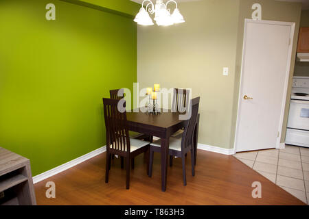 Green walls with a dark wood table and chair set for four in a kitchen or dining area of a home Stock Photo