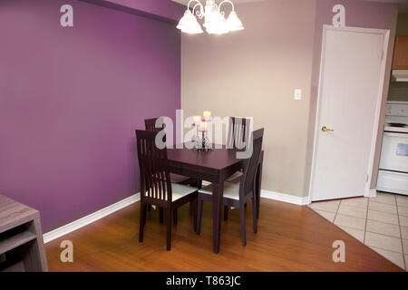 purple walls with a dark wood table and chair set for four in a kitchen or dining area of a home Stock Photo