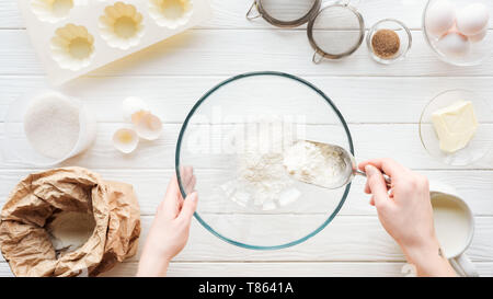 cropped view of woman with scoop putting flour in bowl while cooking on table Stock Photo