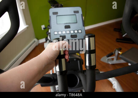 Hand on the elliptical machine at a home gym Stock Photo