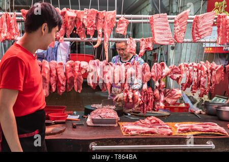 Hong Kong, China - March 8, 2019: Tai Po Market in New Territory. Lots of red meat on display in open air on plates or hanging on hooks at butcher sho Stock Photo