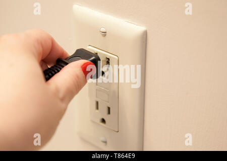 Hand plugging or unplugging a cord into an outlet Stock Photo