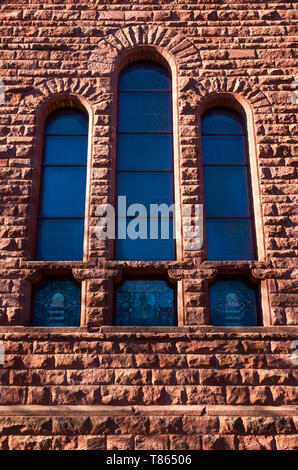 architectural detail of exterior stone wall and stained glass windows Stock Photo