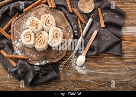 Wooden board with uncooked cinnamon rolls on kitchen table Stock Photo