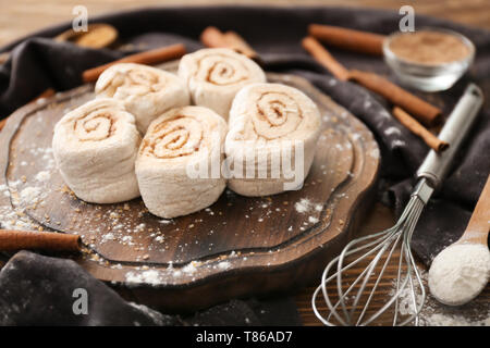 Wooden board with uncooked cinnamon rolls on kitchen table Stock Photo