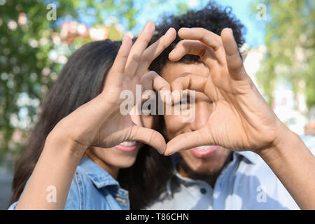 Happy African-American couple making heart with their hands in park Stock Photo