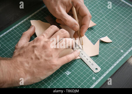 Man working with piece of leather at factory, closeup Stock Photo