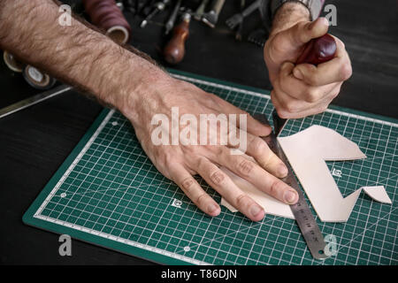 Man working with piece of leather at factory, closeup Stock Photo