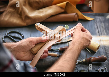 Man using stitching clamp while working with leather at factory, closeup Stock Photo