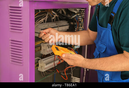 Electrician measuring voltage in distribution board Stock Photo