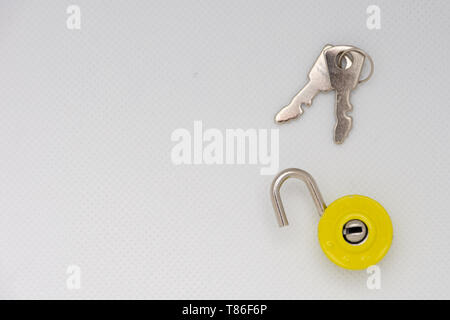 Silver keys and a yellow unlocked padlock on an isolated white background. Freedom and escape. Stock Photo