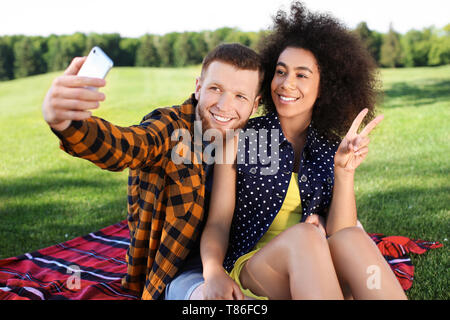 Young loving interracial couple taking selfie outdoors on spring day Stock Photo