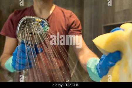Man cleans a glass in the bathroom, with a sponge and water. Stock Photo