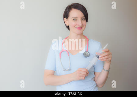 Attractive friendly female doctor holding syringe portrait Stock Photo