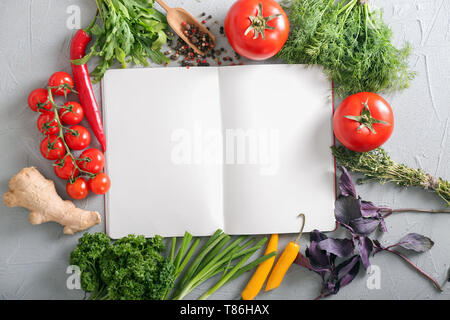Composition with blank notebook, different fresh herbs and vegetables on grey background Stock Photo