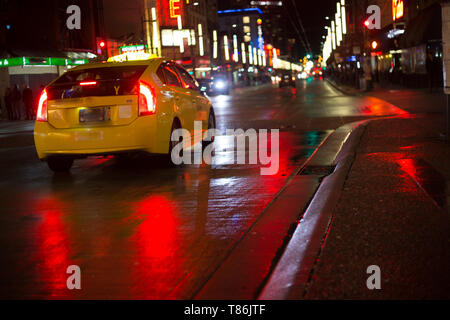 Yellow taxi car driving  rain night city wet asphalt red reflections copy space Stock Photo