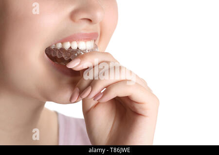 Woman putting occlusal splint in mouth on white background, closeup Stock Photo