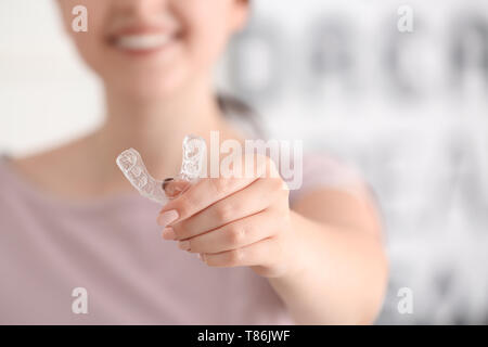 Woman holding occlusal splint on light background, closeup Stock Photo