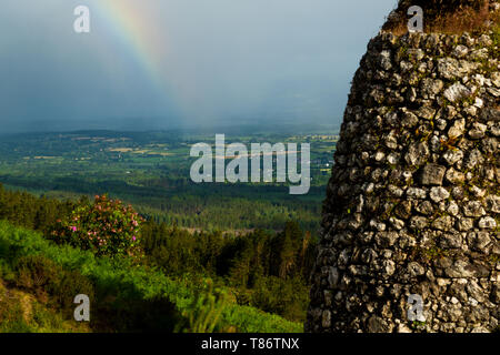 Grubbs monument in The Vee, Country Tipperary, Ireland, with an approaching summer rain storm and rainbow in the valley. Stock Photo