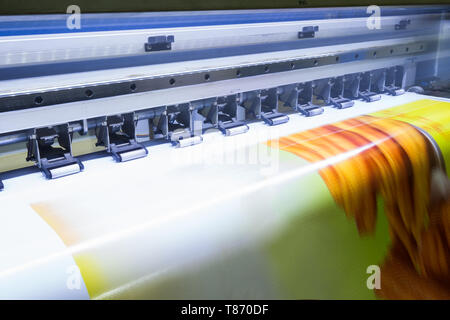Format large inkjet printer working on yellow vinyl banner Stock Photo