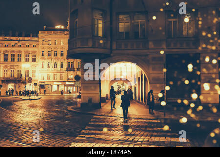 Czech Republic, Prague - December 24, 2018: Night street in a European city with bokeh from Christmas lanterns, silhouettes of people and facades of b Stock Photo