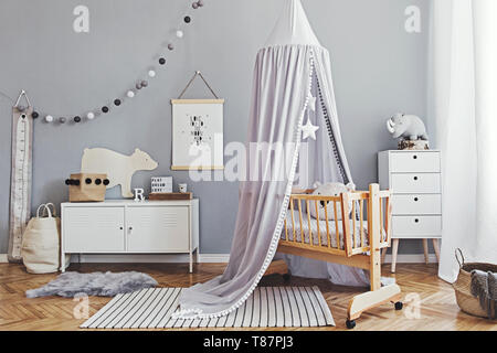 Stylish and modern scandinavian nursery interior with gray walls, brown wooden parquet and design furnitures and accessories. Cozy childroom. Stock Photo
