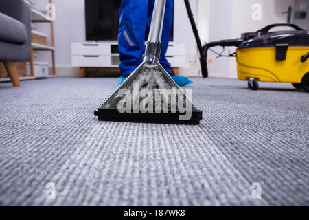 Low Section Of A Person Cleaning The Carpet With Vacuum Cleaner In Living Room Stock Photo