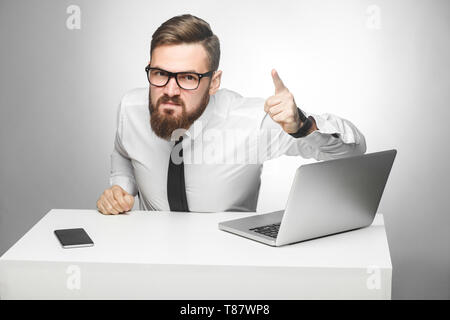 Portrait of aggressive unhappy young businessman in white shirt and black tie are blaming you in office and having bad mood, screaming and pointing fi Stock Photo