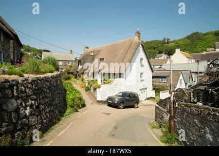 Narrow lane, thatched cottage and parked car in the small pretty fishing village of Cadgwith, Cornwall, England Stock Photo