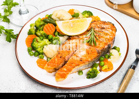 Grilled salmon steak with vegetables on white. Stock Photo