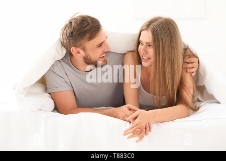 Happy young couple together under blanket in bed at home Stock Photo