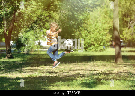 Cute little boy playing football in park Stock Photo