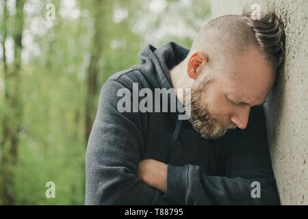 depressed and lonely man his head against a wall Stock Photo