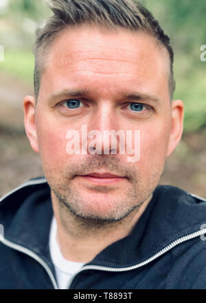 Handsome blue eyed mid adult caucasian close up up face portrait outdoors with forest background Stock Photo